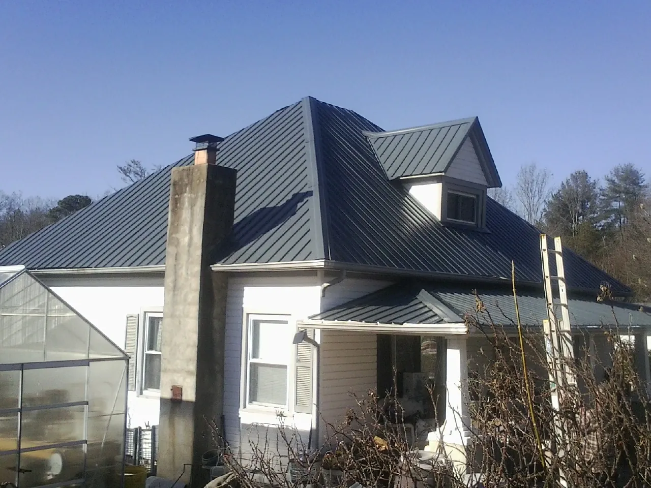 Dark blue standing seam metal roof on a white farmhouse with dormer — Slate & Tile Roof Repair by Roofing Brothers in Pablo