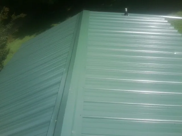 New green metal panels meeting at the ridge of a roof — Flat Roof Repair work by our crew in Pablo