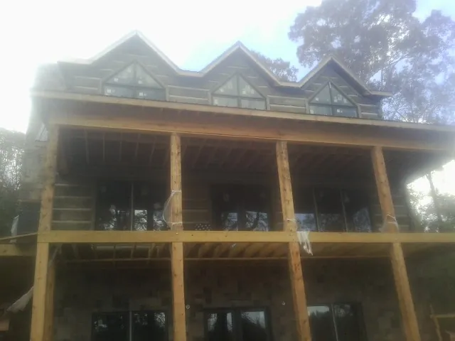 Dormers and porch framing on a large log home under construction — Roof Coating work by our crew in Pablo