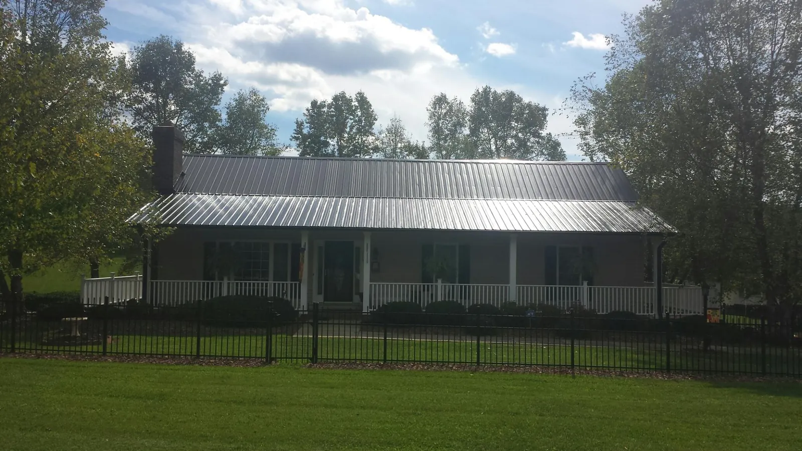 Gray metal roof on a brick ranch with a full width front porch — Gutter Guard Installation work by our crew in Pablo