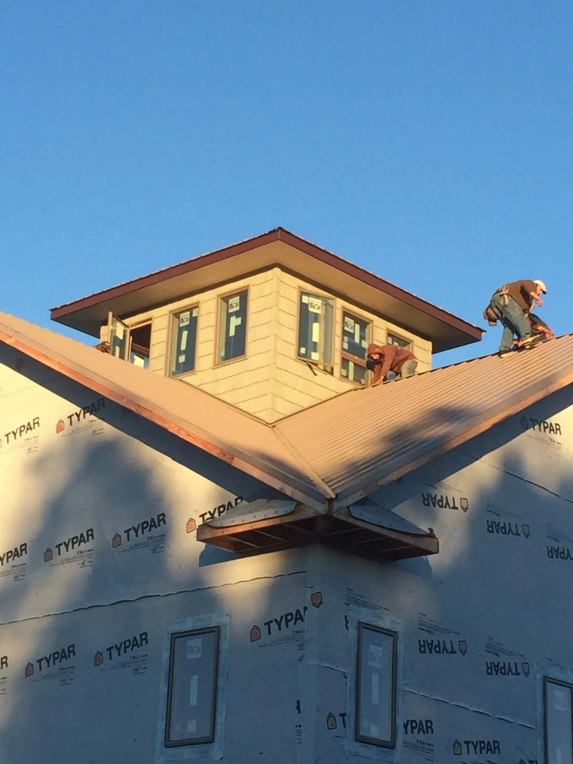 Roofers working around a rooftop cupola on a new metal roof at sunset — Roof Waterproofing in Pablo by Roofing Brothers